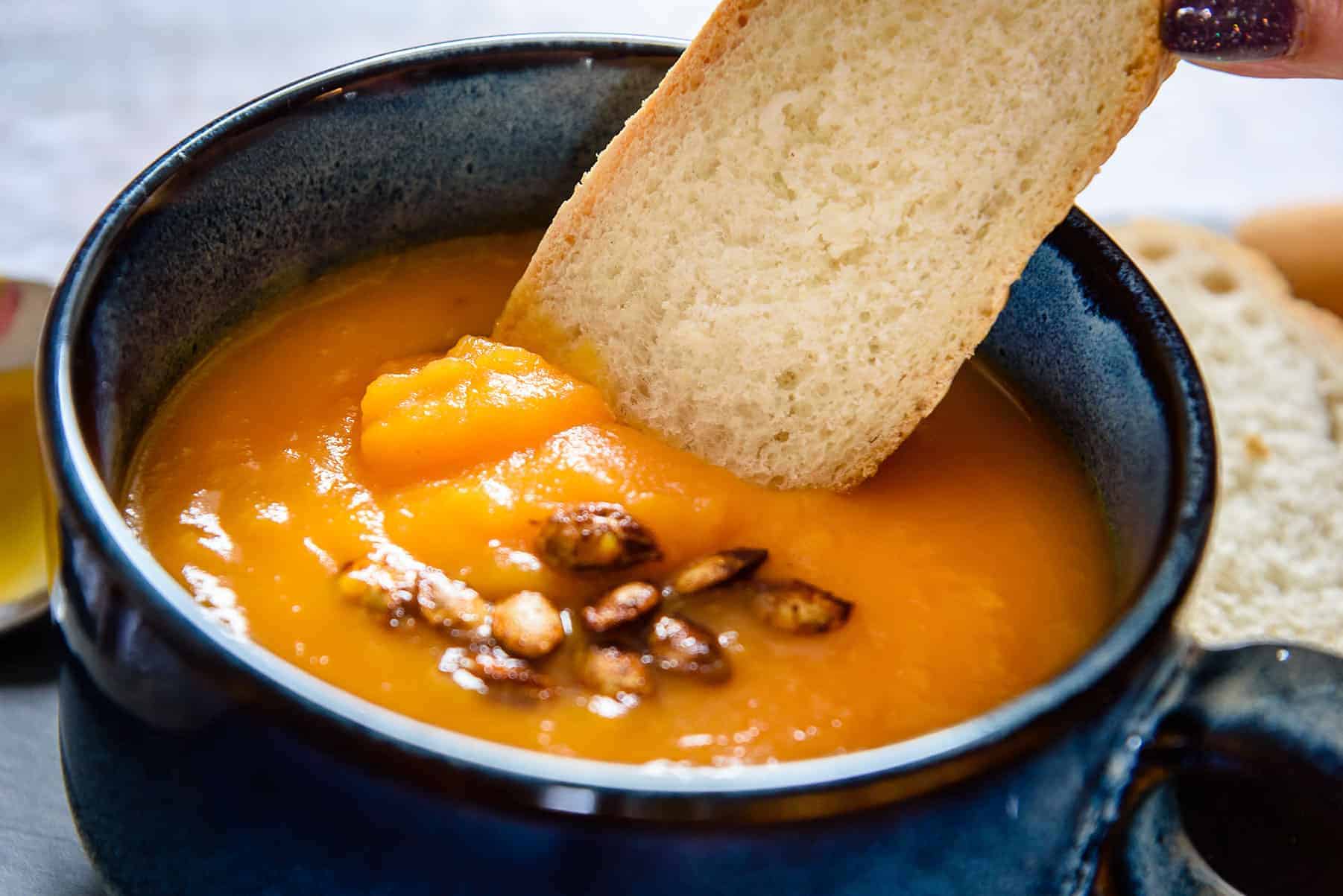 Dipping bread into Vegan Butter-Roasted Butternut-Squash Soup