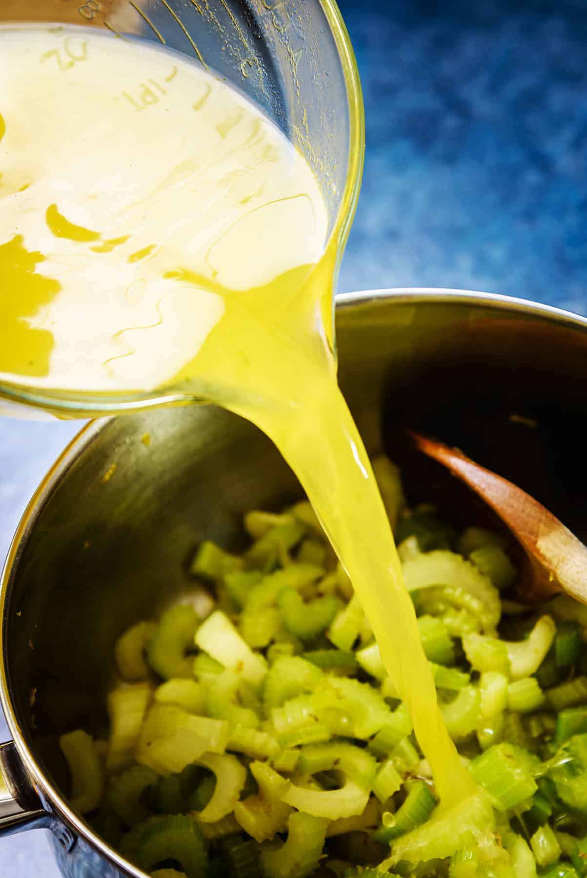 Pouring the stock into the pan of sliced celery