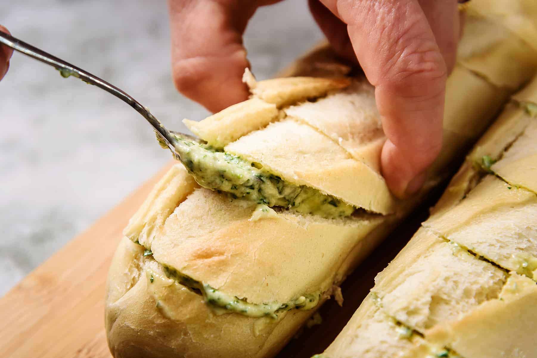 Placing the garlic butter in the baguette slices