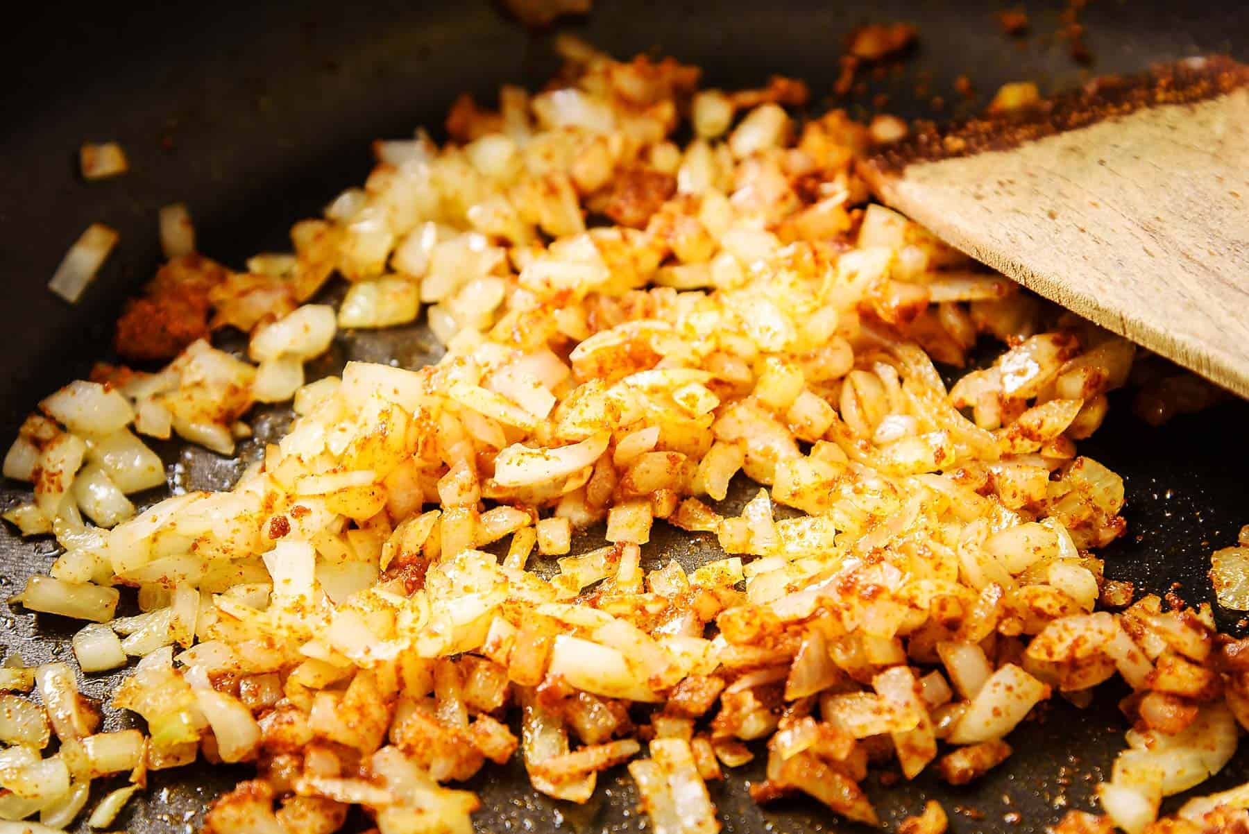 Adding the curry powder to the onions in the pan