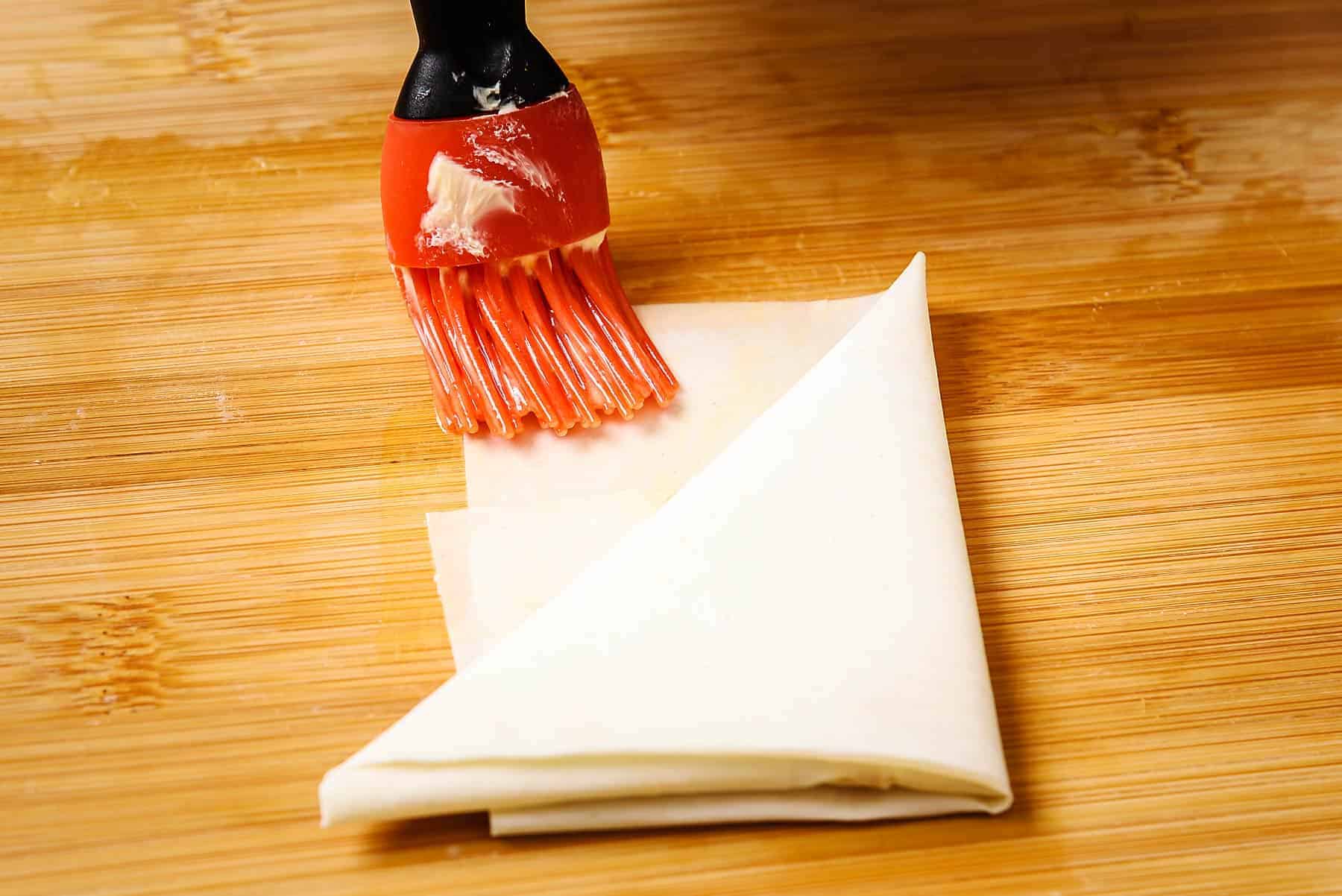 Brushing end of filo pastry with melted butter