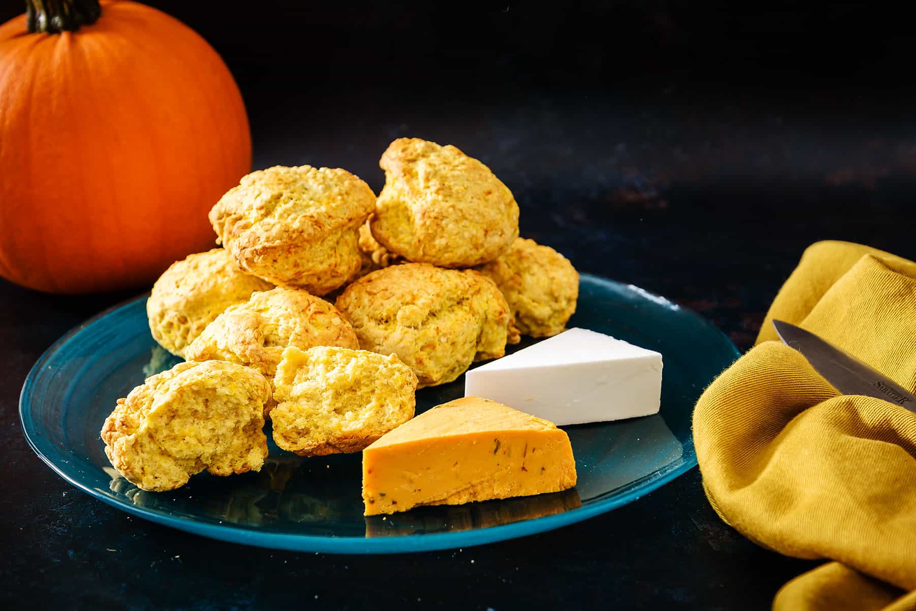 Vegan Rustic Pumpkin Scones on a serving plate with vegan cheeses