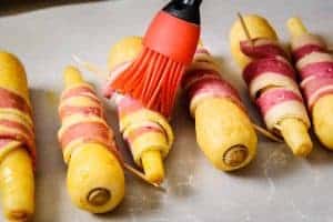 Brushing the bacon-wrapped parsnips with oil