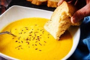 Dipping bread into Vegan Carrot & Chickpea Soup