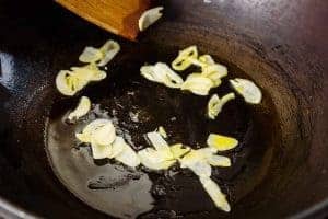 Adding sliced garlic to the wok