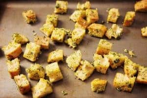 Coated bread cubes on an oven tray for baking