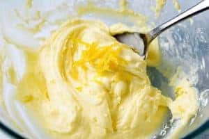 Adding the lemon zest to the icing mixture in a bowl