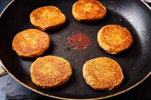 6 patties cooking in a frying pan