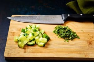 Chopped cucumber and mint on a chopping board with knife