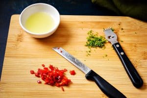 Chopped red jalapeno chilli and lime zest and juice on a chopping board with knife and zester