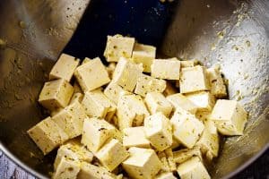Mixing the tofu cubes into the whisked dressing