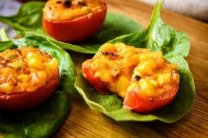 Stuffed Spicy Baked Tomatoes cut open on a spinach leaf
