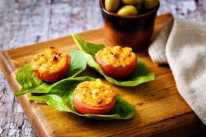 Stuffed Spicy Baked Tomatoes served on a spinach leaves